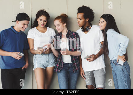 Teen girl showing joke on phone to diverse friends Stock Photo