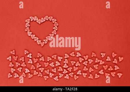 Heart of coral wooden buttons in the form of hearts on a coral paper background Stock Photo