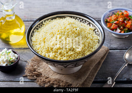 Couscous in bowl with olive oil. Wooden background. Close up. Stock Photo