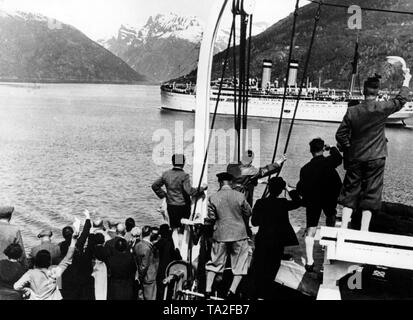 Undated photo of vacationers of the Nazi organization 'Kraft durch Freude' ('Strength Through Joy') on a KdF ship, who welcome another KdF ship in a fjord on the Norwegian coast. In the background, snow-covered mountains. Stock Photo