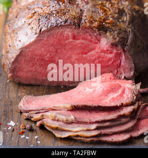 Roast beef on cutting board. Wooden background. Close up. Stock Photo