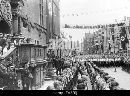 During his visit to Gdansk, the Minister of Propaganda, Joseph Goebbels, addresses to members of the Gdansk Youth Hitler Youth and BDM in front of the Town Hall of Gdansk. Across the street is a banner reading: 'Danzig's population greets the conqueror of Berlin.' The stairs of the Town Hall are guarded by SS and SA members. Stock Photo