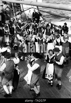 During a sea voyage to Madeira, a group of vacationers from Winningen/Mosel are dancing in Palatinate costumes on the stern of the cruise ship 'St. Louis' that belonged to the Nazi organization 'Kraft durch Freude' ('Strength through Joy'). Stock Photo