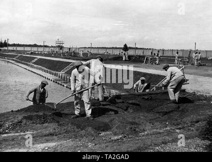 Prisoners in the Dachau concentration camp during excavation work for the construction of a swimming pool: one of the propaganda pictures of the Nazi regime. Stock Photo