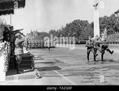 Photo of a color guard of the Condor Legion marching in front of officers of the Wehrmacht and Adolf Hitler (under a canopy, on the left, commander Major General Wolfram Freiherr von Richthofen) on the East-West Axis (former Chalottenburger Chaussee, today Strasse des 17. Juni ) in front of the Technische Universitaet on June 6, 1939. In the background the Grandhotel am Knie (today Ernst Reuter Platz). Stock Photo