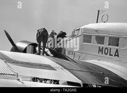 Photo of the wing, cockpits and engines of a German Junkers Ju 52 of the Spanish airline Iberia 1939 at the airport of Salamanca, Castile and Leon, Spain. Mechanics are working on one of the engines. The machine is named "Mola", after general Emilio Mola Vidal (died 1937), one of the leaders of the uprising of General Francisco Franco. During the Civil War, the Deutsche Lufthansa and the Iberia (founded in 1927) carried out scheduled flights mostly with German pilots in the Spanish national zone from 1937. The aircraft were provided by the Deutsche Lufthansa AG. Stock Photo