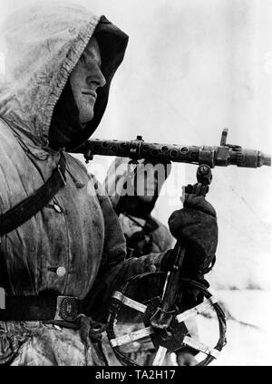 German soldiers during winter fighting near the city of Toropez at the northern section of the Eastern Front. A soldier carries a Maschinengewehr 34 on his shoulder, in his hand he holds a bipod, which is to prevent the sinking of the machine gun into the snow. Photo of the Propaganda Company (PK): war correspondent Hermann. Stock Photo