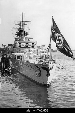 Photo of the rear of the heavy cruiser 'Deutschland' at the great naval review in Swinoujscie (Poland) at the Szczecin Lagoon in the Baltic Sea. The warship is anchored in the harbor.  Here, the imperial eagle with a swastika, as well as the naval ensign of the German Reich at the stern. Behind, the rear turret with three 28 cm quick-firing guns. Stock Photo