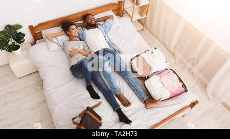 Ready For Journey. Couple Lying On Bed Stock Photo