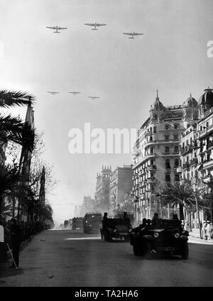 Photo of a victory parade of Spanish national units, including the Condor Legion, on Passeig De Colon after the conquest (January 1939) of Barcelona by General Francisco Franco on February 21, 1939. Two German tractors, type Krupp L2 H143, are on the road. In the sky, three Heinkel He 111 bombers in formation flight. Stock Photo