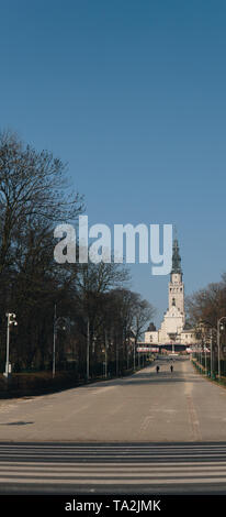 path through a park with a church tower at the end Stock Photo