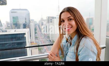 Attractive city woman over the rooftops of Sao Paulo with view to the skyline and the Paulista Avenue, Brazil Stock Photo