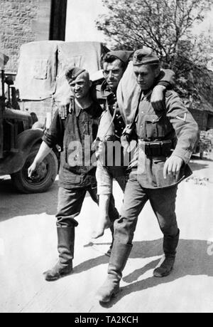 Two German soldiers carry a French prisoner of war to the dressing station. Photo. Brenner. Stock Photo