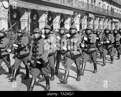 Photo of a guard troop unit of the Spanish national faction at a parade at Plaza Mayor in Salamanca, Castile and Leon, Spain, 1937. The soldiers wear boots, beketsches, helmets and white gloves and are armed with carabiners and fixed bayonets. In the background, the awning of a wholesale firm. Stock Photo