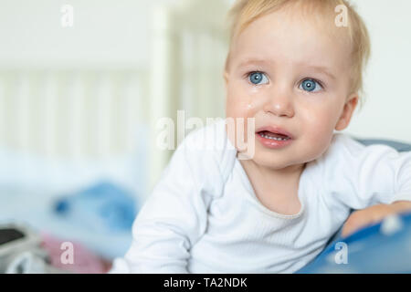 Cute caucasian blond toddler boy portrait crying at home during hysterics. Little child feeling sad. Small pensive baby after quarell. Stock Photo