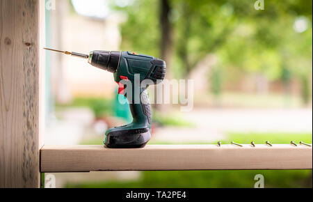 Electric cordless drill on wooden surface with some screw Stock Photo