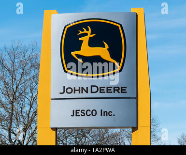 Deer Park, New York, USA - 17 April 2019: A gold John Deere sign with a blue sky in the background in front of a office. Stock Photo