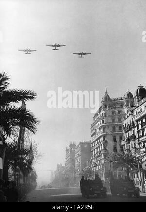 Photo of a victory parade of Spanish national units, including the Condor Legion, on Passeig De Colon after the conquest (January 1939) of Barcelona by General Francisco Franco on February 21, 1939. Two German tractors, type Krupp L2 H143, are on the road. In the sky, three Heinkel He 111 bombers in formation flight. Stock Photo