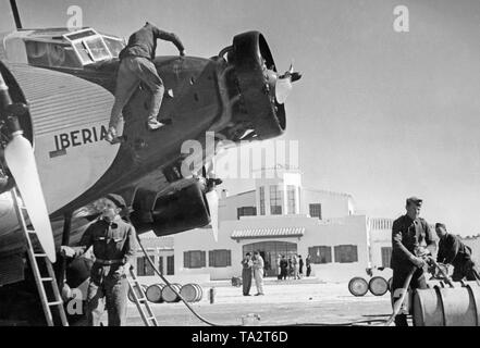 Photo of the cockpits and engines of a German Junkers Ju 52 of the Spanish airline Iberia 1939 at the airport of Salamanca, Castile and Leon, Spain. Mechanics are working on one of the engines. The machine is named "Mola", after general Emilio Mola Vidal (died 1937), one of the leaders of the uprising of General Francisco Franco. During the Civil War, the Deutsche Lufthansa and the Iberia (founded in 1927) carried out scheduled flights mostly with German pilots in the Spanish national zone from 1937. The aircraft were provided by the Deutsche Lufthansa AG. Stock Photo