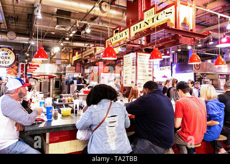 Philadelphia, Pennsylvania USA - 26 April 2019: The inside of Reading Market at lunch time with a counter full of patrons eating at Tommy Dinic's. Stock Photo