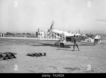 Photo of a German fighter, type Messerschmitt Bf 109, of the Fighter Squadron 88 of the Condor Legion during a take-off on a Spanish airfield. At the rear there is the saltire of the Spanish Air Force. In the background there are buildings and other aircrafts: Junkers Ju 52, Fieseler Storch. In the foreground are aerial bombs. Stock Photo