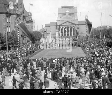 A crowd of people celebrates the liberation of Duisburg with hoisted flags in front of the State Theater. Stock Photo