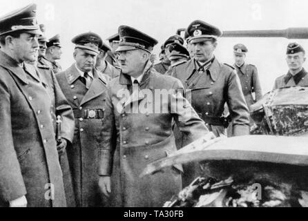 Reich Minister Albert Speer (left) having a conversation with Adolf Hitler (center) during the inspection of products of the defense industry, here a tank. Karl Saur stands between Speer and Hitler, to the right of Hitler, Friedrich-Wilhelm Holzhaeuer. Stock Photo