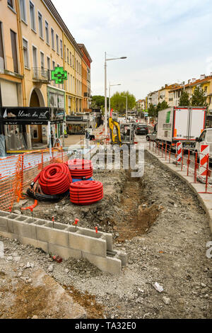 SAN RAPHAEL, FRANCE - APRIL 2019: Mini excavator behind a long trench dug as part of improvements being made to the town centre in San Raphael. Stock Photo