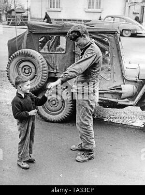 An American soldier gives a boy chewing gum. After the end of the war, many US soldiers were surprised that they did not experience any opposition from the German population. Stock Photo