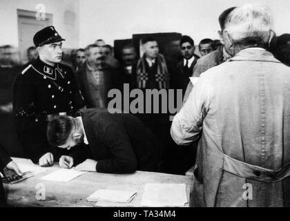 After the Reichstag election victory in November 1933, the Nazi government ordered the release of of about 6,000 political prisoners from the concentration camps as part of a 'Gnadenaktion' (act of mercy) at Christmas. Here, the amnestied men sign their discharge papers in the presence of the guards Dachau Concentration Camp. Stock Photo