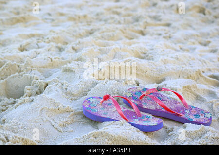 Pair of vivid colored flip-flops sandals on the sandy beach Stock Photo