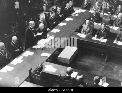 Mayor Karl Scharnagl, who was appointed by the Allies speaks to the 36 city councilmen during the first council meeting in the small meeting room of the Munich Town Hall. On the left is the police president Pitzer (?), at right the second mayor and head of the Munich city administration Franz Stadelmayer. City councilmen Dr. Anton Fingerle, (7th from left) and Dr. Eugen Roth (right, 1st row in the middle, facing). Stock Photo