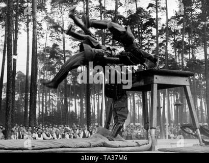 In the established city of the Nazi organization 'Kraft durch Freude' ('Strength through Joy') at the Valznerweiher, uniformed officials of the Schutzpolizei from Berlin do gymnastics exercises on the trampoline in front of spectators during the Nuremberg Rally of the NSDAP. Stock Photo