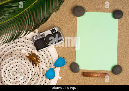 Vacation, travel and summer concept - notebook with palm leave, hat and vintage photo cameraon beach sand Stock Photo