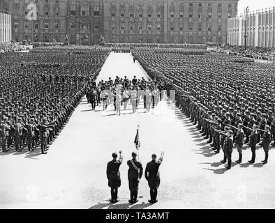 Adolf Hitler and Field Marshal General Hermann Goering (middle, the first row), along with other prominent figures (including Major General Wolfram von Riochthofen, Grand Admiral Erich Raeder, General Wilhelm Keitel, General der Flieger Hugo Sperrle, SS leader Heinrich Himmler), are marching through the Lustgarten in Berlin-Mitte among the lines of the Condor Legion (giving the Hitler salute) towards the lectern in front of the Altes Museum. They are received by color guards of the Legion. In the background, the facade of the Berlin Palace. Stock Photo