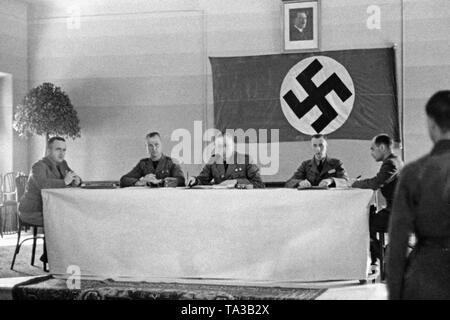Undated photo of the three leaders (from left to right): lieutenant, colonel, corporal with sword knot and assessor of a military court of the German Condor Legion during the Spanish Civil War in 1939. In the background, a swastika flag and a portrait of Adolf Hitler. Stock Photo
