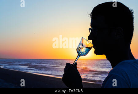 Silhouettes of Man drink glasses of champagne wine at sunset yellow sky. Empty Copy space for inscription Stock Photo