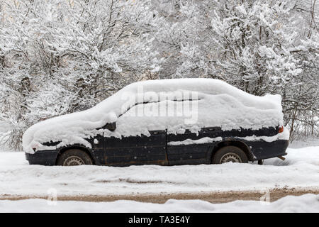 Old dirty car covered by thick snow layer with selective focus. Stock Photo