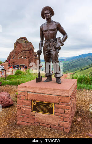 A bronze statue honors Civilian Conservation Corps workers who built the scenic Red Rocks Park Amphitheater in distance, Morrison Colorado US. Stock Photo