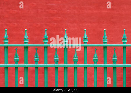 Rod Iron Fence in Green with Red Background Stock Photo