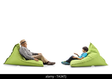 Full length profile shot of a grandfather and grandson sitting on bean bags isolated on white background Stock Photo