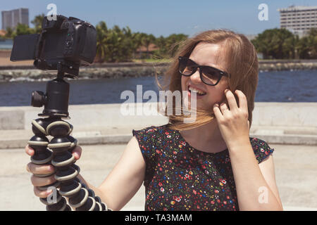 Camera recording a young caucasian female blogger gesturing while making a video Stock Photo