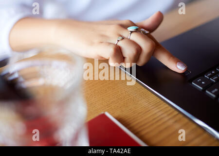 Close up photo of woman touching laptop fingerprint sensor with her finger to log in into system. Biometric fingerprint print scan provides security a Stock Photo