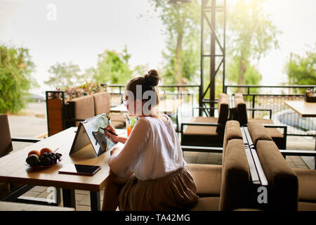 Digital artist drawing sketch with stylus on convertible to in 1 laptop display in tent mode in cafe. Mixed race multiethnic asian caucasian woman wor Stock Photo