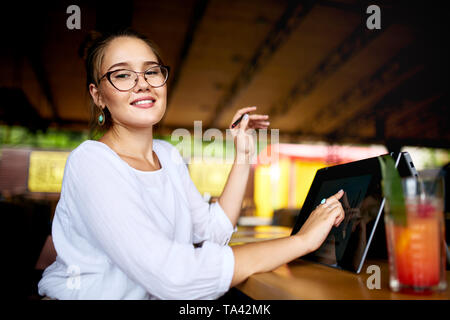 Digital artist drawing sketch on convertible to 2 in 1 laptop display in tent mode and holds stylus in her hand. Mixed race multiethnic asian caucasia Stock Photo