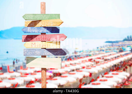 Wooden arrow signs in front of the beach unbrellas Stock Photo