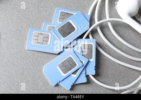 Sim cards and earphones on grey background Stock Photo