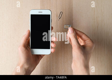 Woman inserting sim card into mobile phone, top view Stock Photo