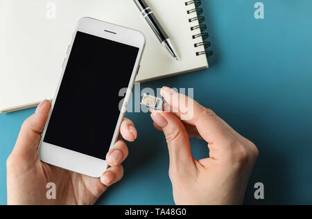 Woman inserting sim card into mobile phone, closeup Stock Photo