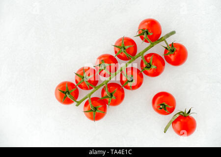 Arrangement of cherry tomatoes on white textured and patterned background with copy space. Top view. Stock Photo
